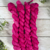 four skeins of pink yarn on a table