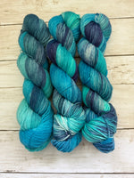 Blue and green skeins of yarn on a wooden surface