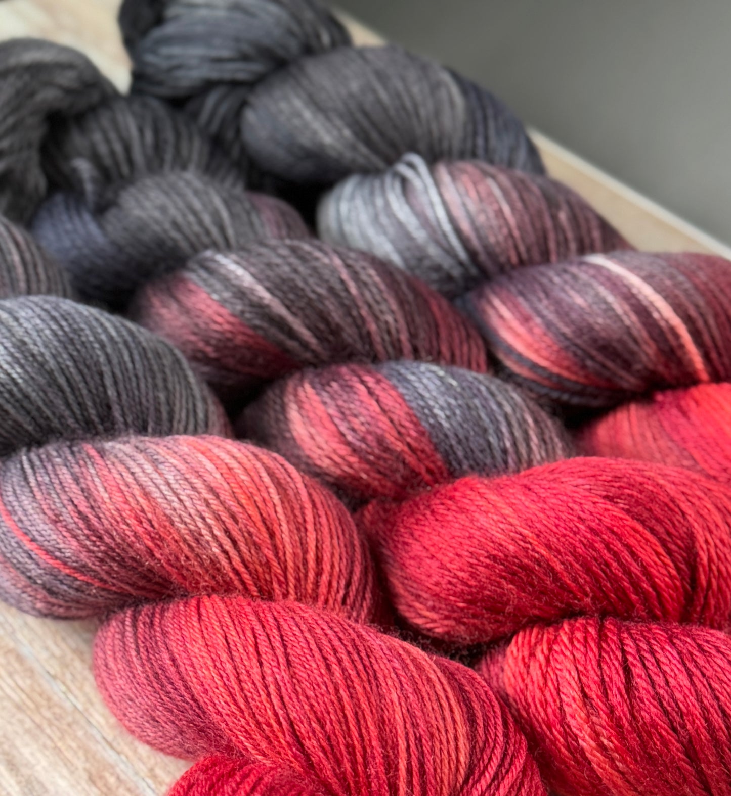 Grey and red yarn on a wood table