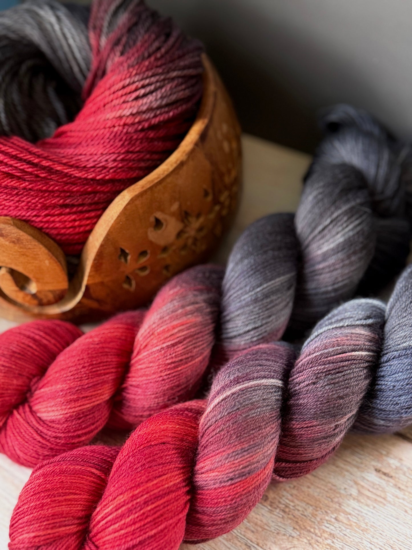 Grey and red yarn on a wood table