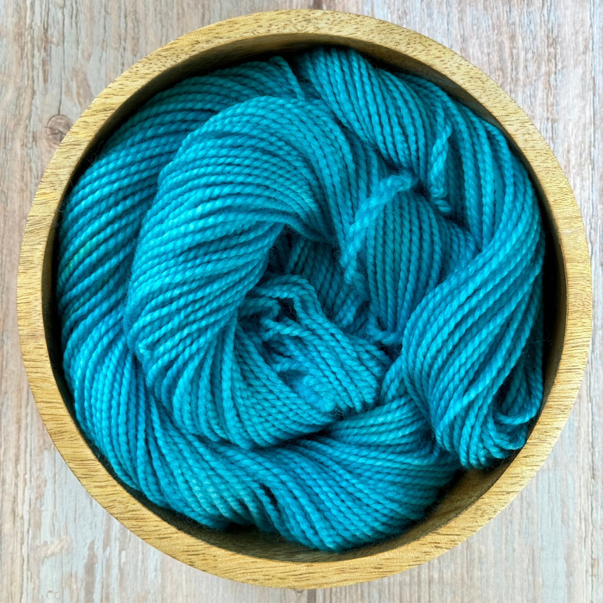 A blue skein of yarn in a wooden bowl