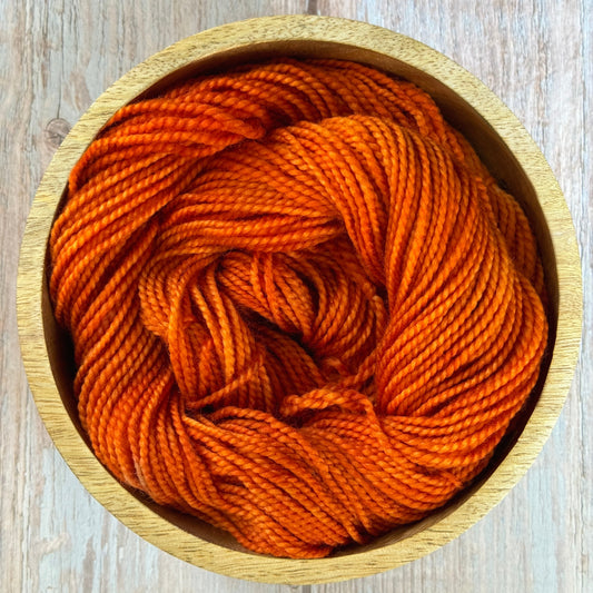 Orange yarn in a wooden bowl