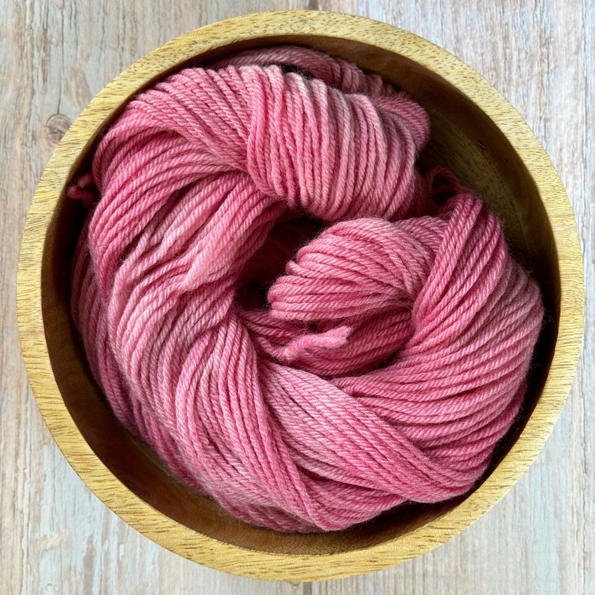 Pink yarn in a wooden bowl