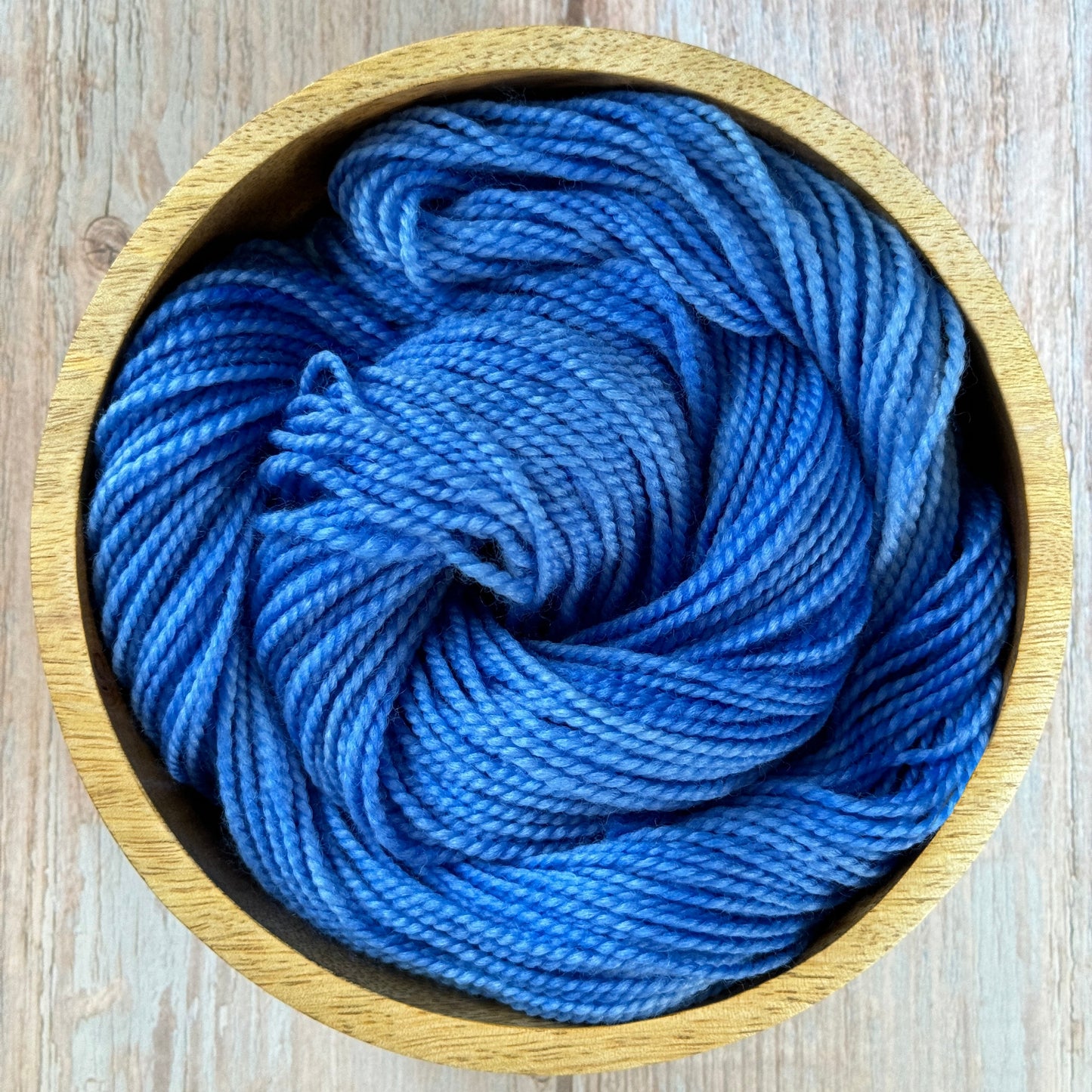 A wooden bowl with blue yarn