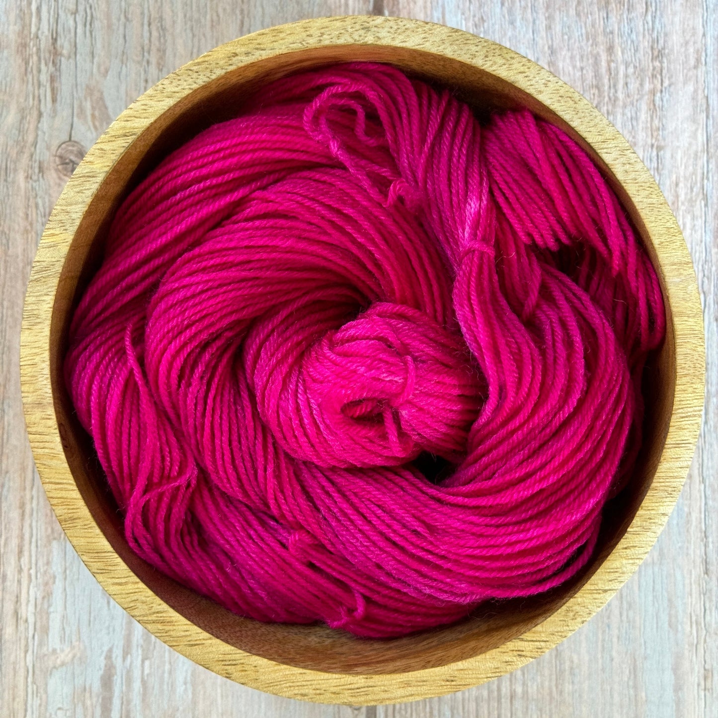 Pink yarn in a wooden bowl