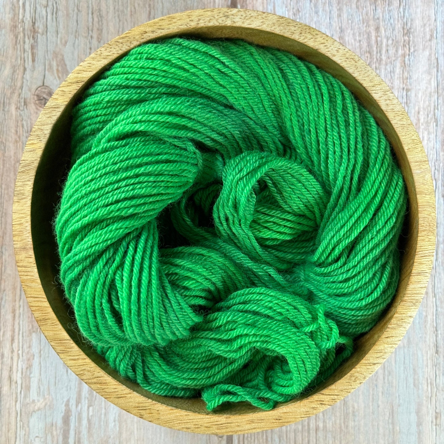 Green yarn in a wood bowl