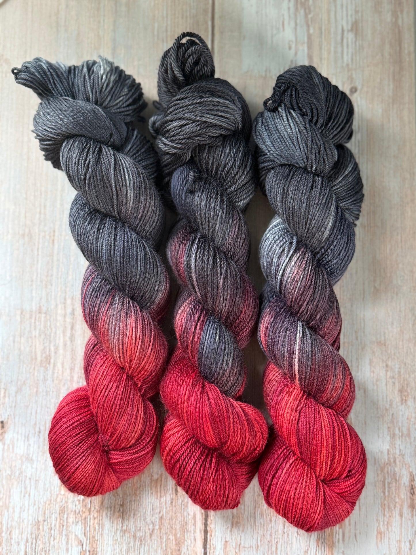 Grey and red yarn on a wood table