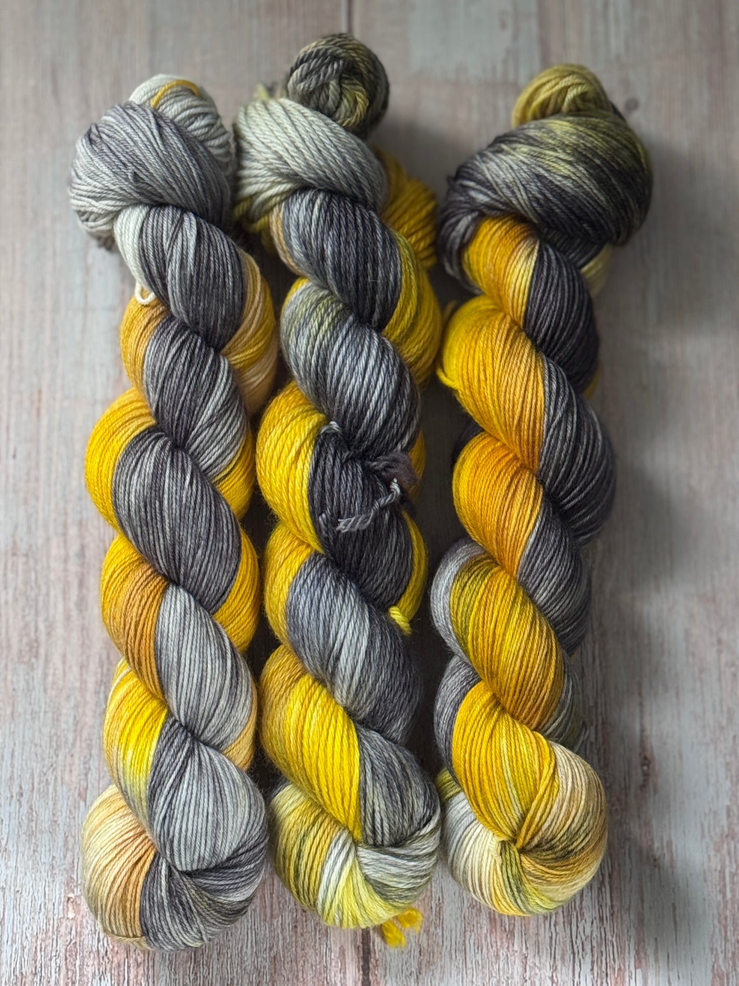 Three skeins of grey, black, and yellow yarn