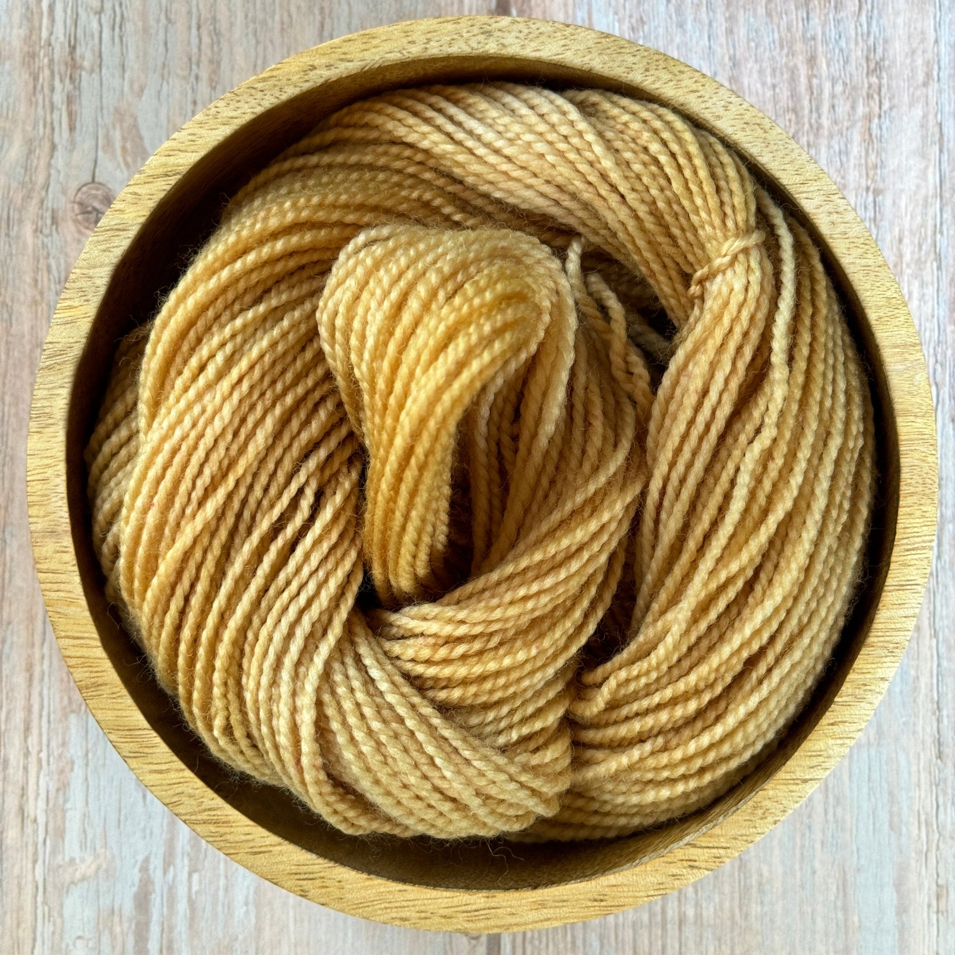 Yellow yarn in a wooden bowl