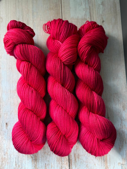 three skeins of red yarn on a wooden surface