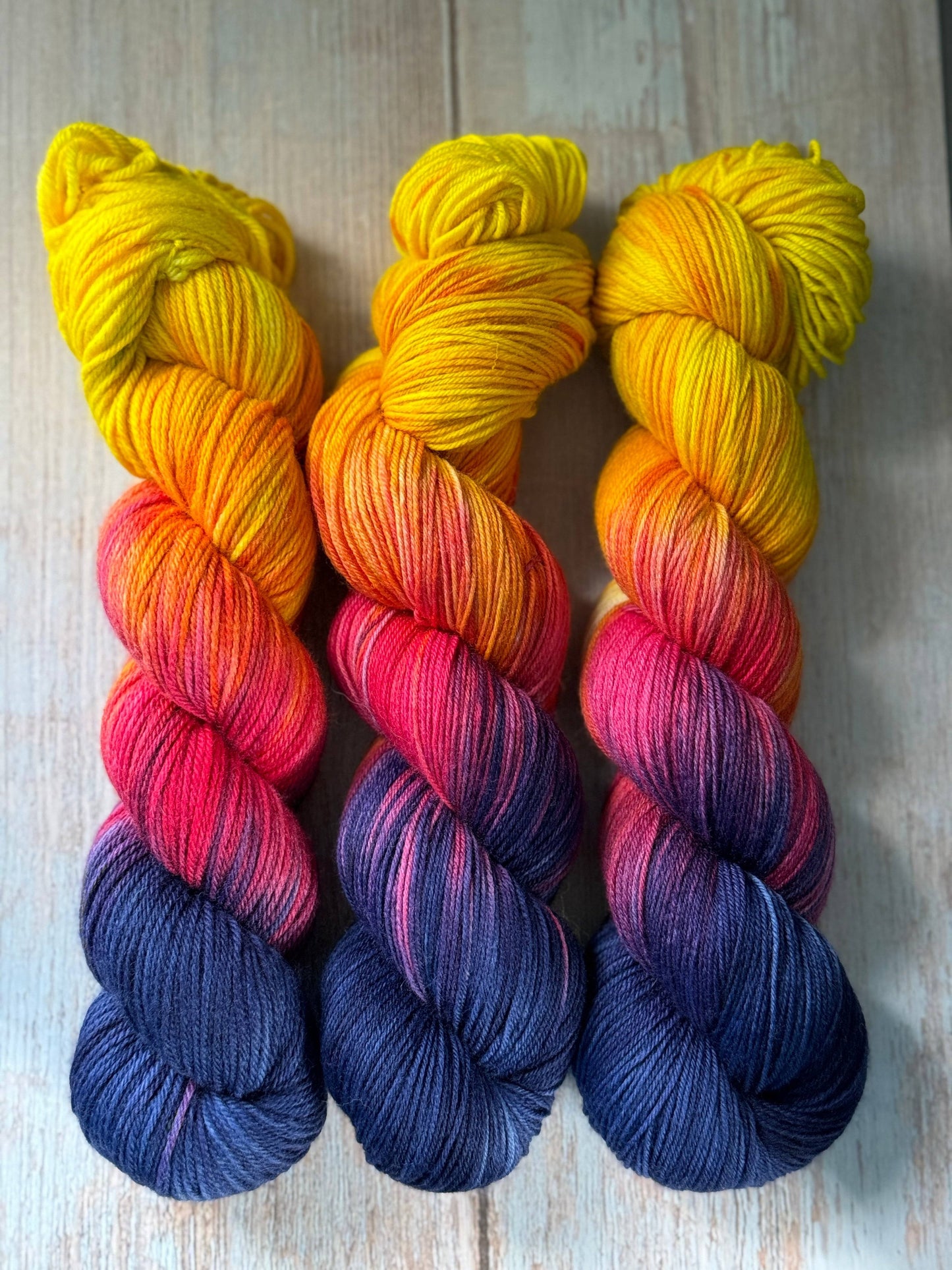 three skeins of multicolored yarn on a wooden surface