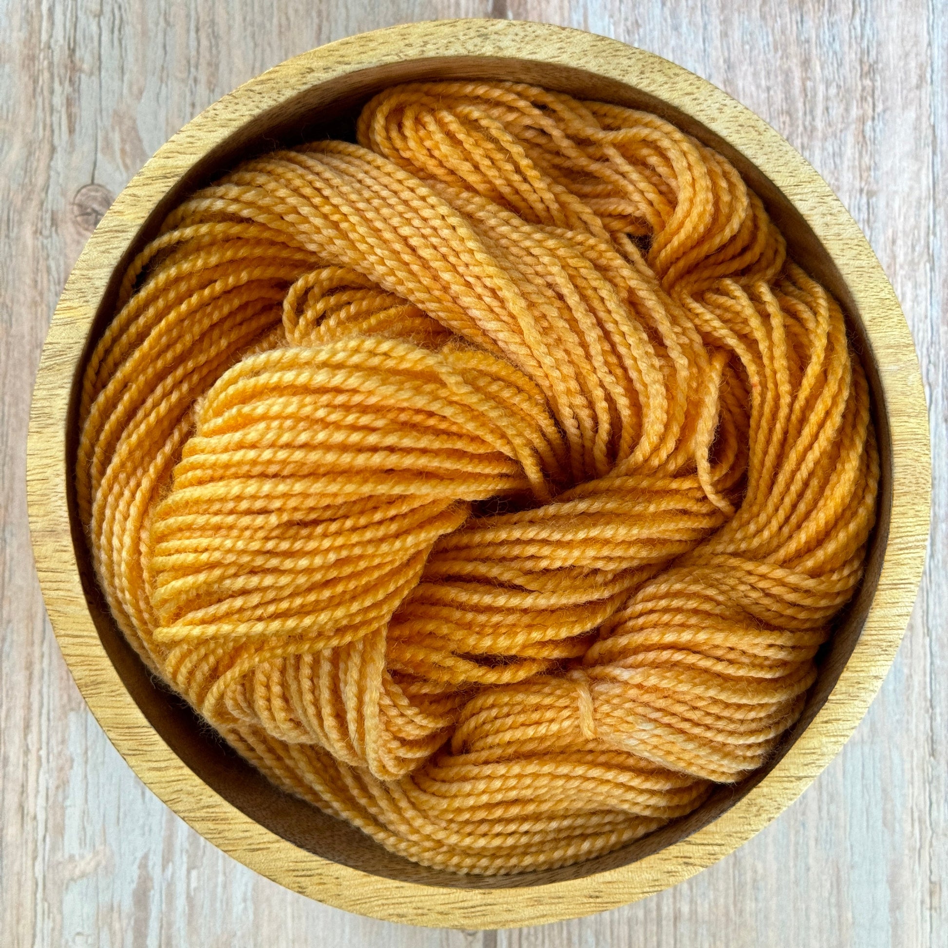 Yellow yarn in a wooden bowl