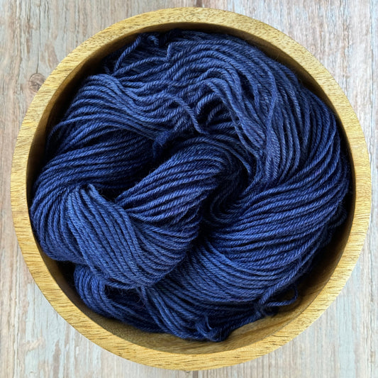 a blue skein of yarn in a wooden bowl