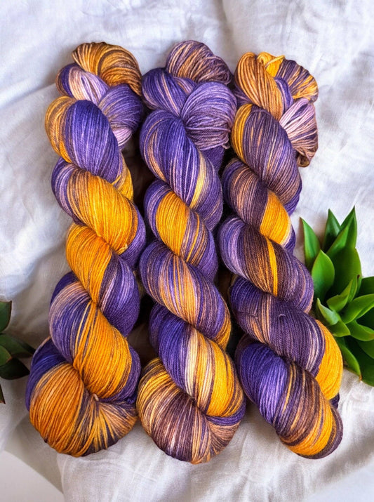 Three skeins of purple and gold yarn