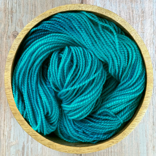 a blue skein of yarn in a wooden bowl