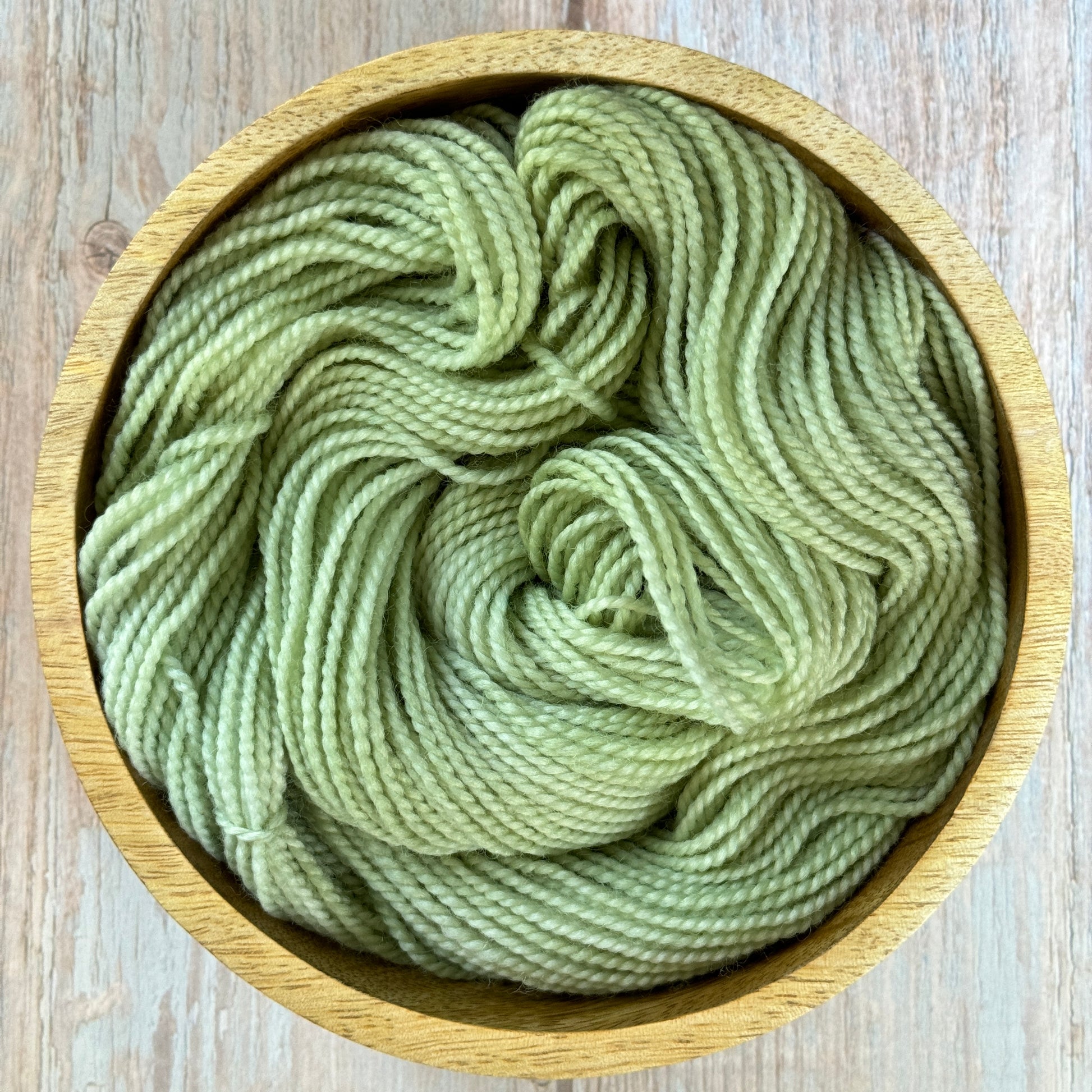 Green yarn in a wood bowl